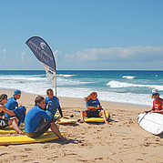 Surf instructor explaining your surfboard Your surf instructor shows you step by step how to handle your surfboard safely – the foundation of every beginner surf course.