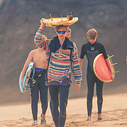 Family on the beach on the way to surf